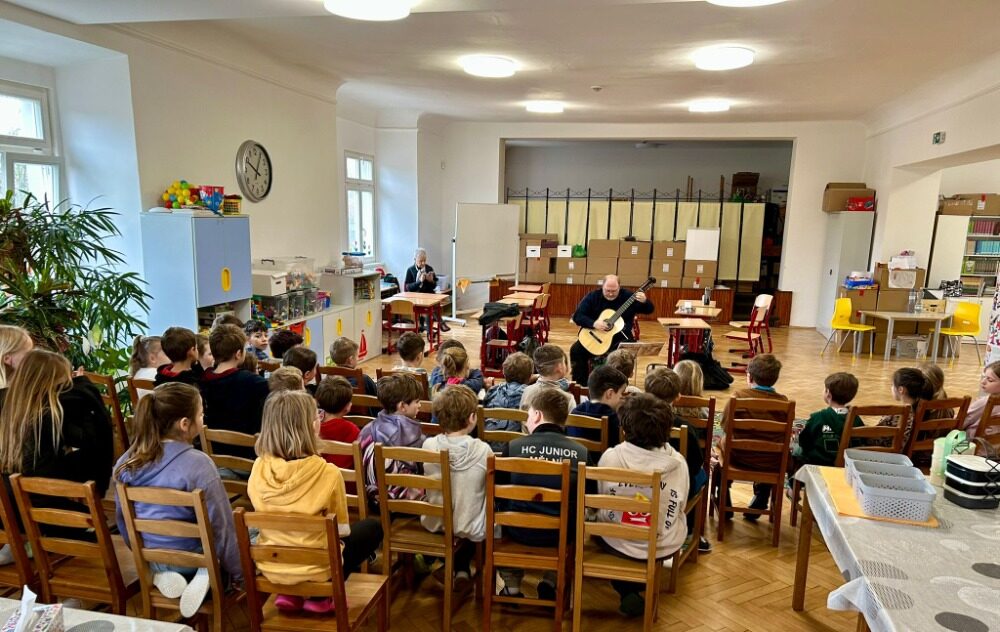 Žáci sledují hudební program s kytarou ve školní družině